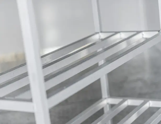 Close-up of an empty white metal storage shelf with parallel bars against a softly blurred background.