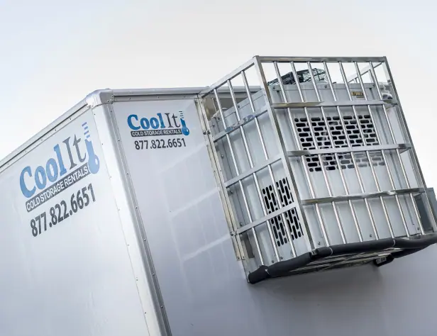 Cool It refrigerated truck with a cooling unit in a metal cage, displaying a phone number against a clear sky.
