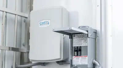 Industrial electrical disconnect switch mounted on a white wall next to a CleanLift branded enclosure.