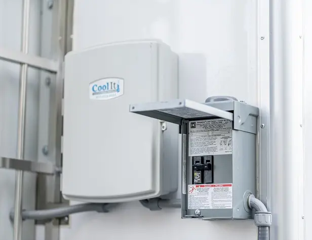 Industrial electrical disconnect switch mounted on a white wall next to a CleanLift branded enclosure.