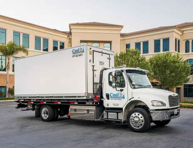 Coolife white refrigerated delivery truck parked in front of a beige office building lined with palm trees.